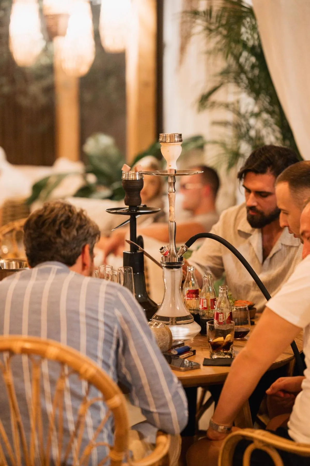 Grup in jurul unei narghilele din sticla cu bauturi pe masa la Komodo Lounge