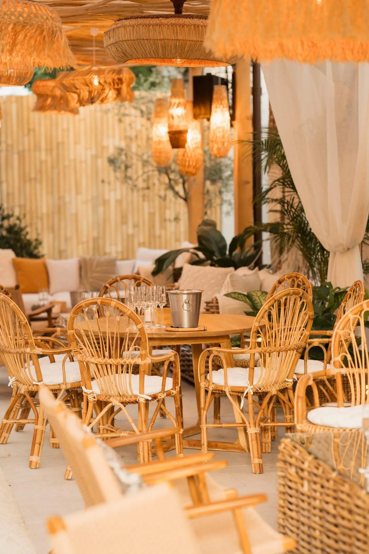 Terasa Komodo Lounge pregatita pentru seara — scaune din ratan in jurul unei mese de lemn cu sampanie la gheata