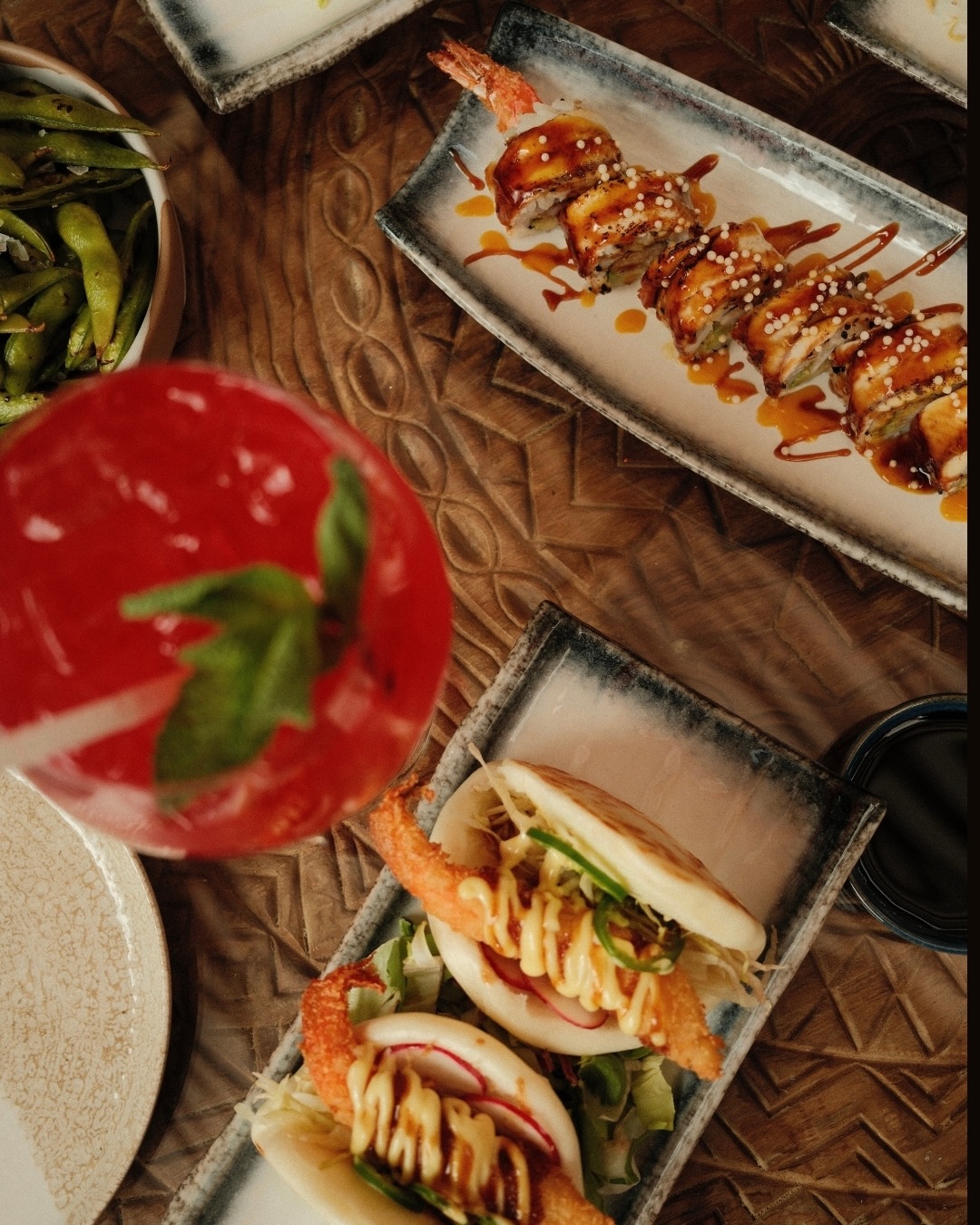 Overhead spread of sushi, bao and cocktail