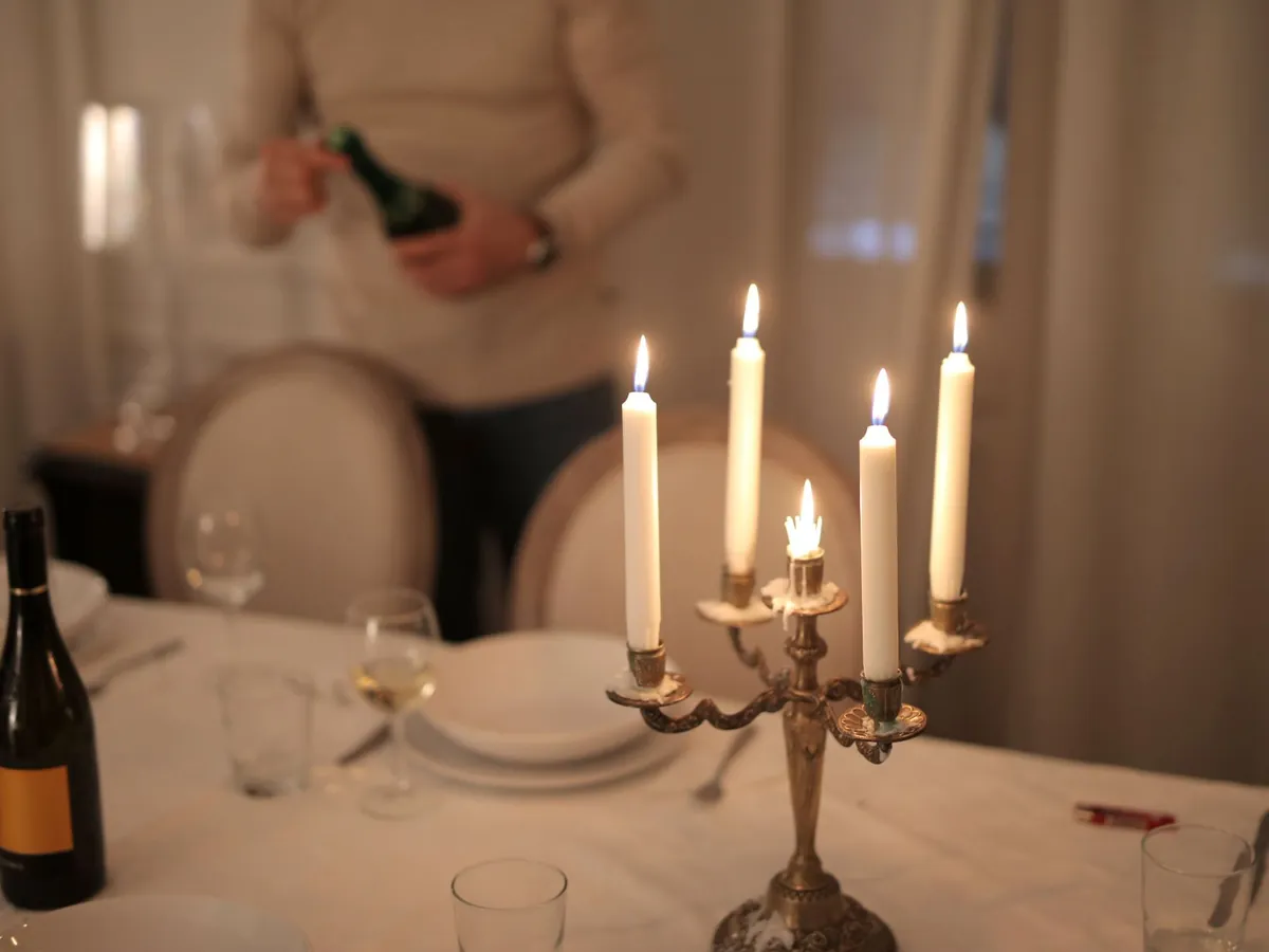 Masă de cină pentru doi, la lumina lumânărilor, cu vin turnat